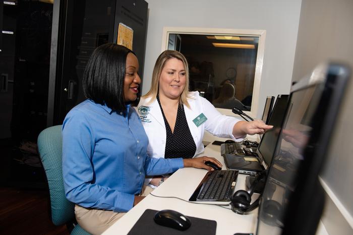 Nursing instructor and students checking information on a computer screen.